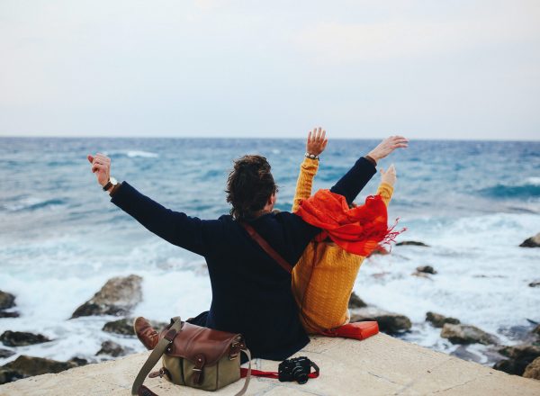 Couple in love sits on the quay, and looks at the sea, they feel freedom